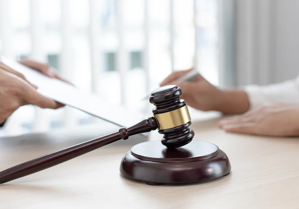 A gavel resting on a desk while two people review a document