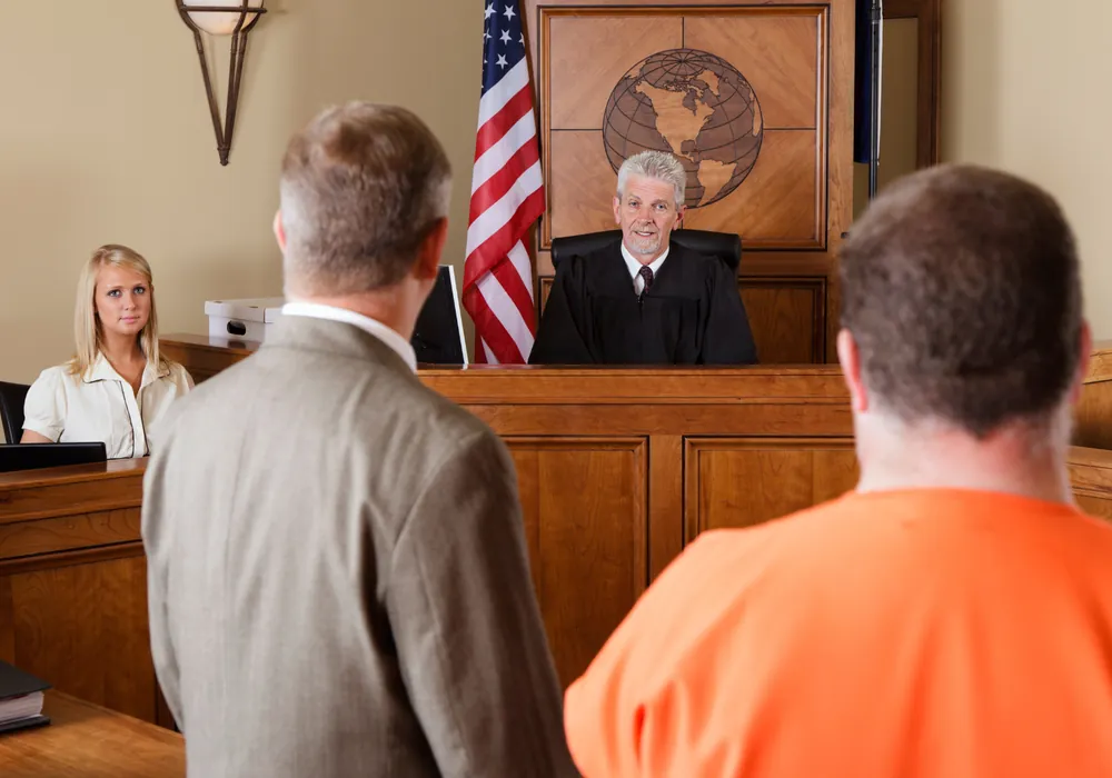 A defendant and defense attorney standing before a judge during a criminal hearing