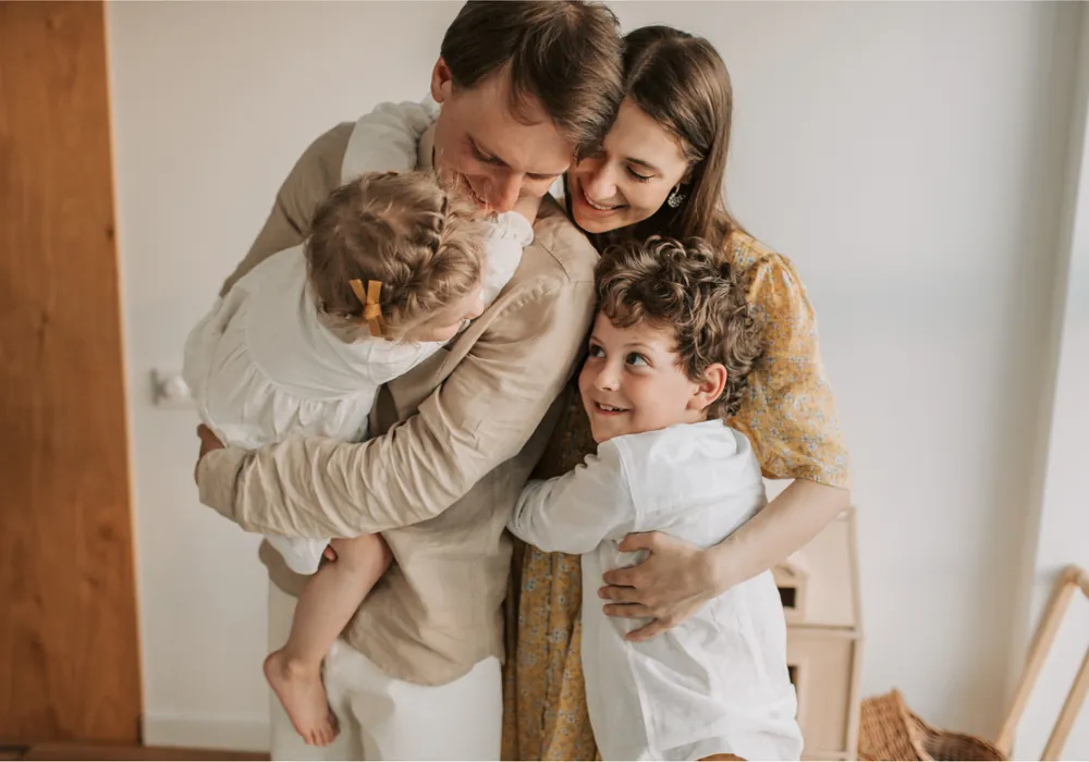 Two parents holding their young son and daughter in a bright room