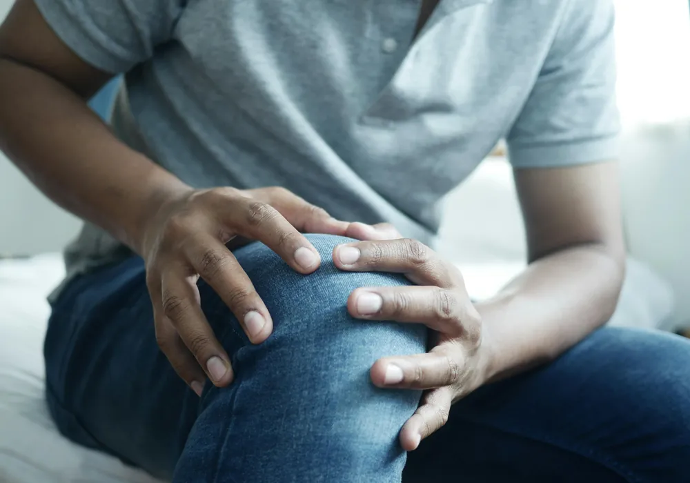 A seated man holding his knee with both hands
