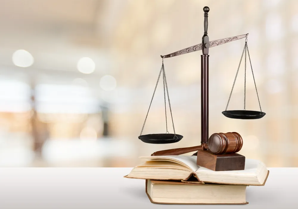 Brass scales of justice and a gavel resting on a stack of open law books